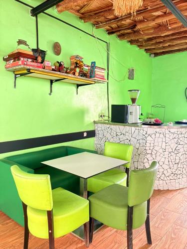 a restaurant with green walls and a table and chairs at ASARAG GUEST HOUSE & Lodge in Mirleft