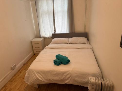 a small bed with a green stuffed animal on it at Rahal Hotel Hackney London in London