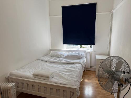 a bedroom with a bed with a fan and a window at Rahal Hotel Hackney London in London