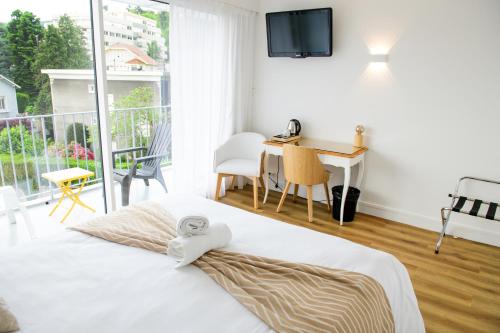 une chambre avec un lit et un bureau et un balcon dans l'établissement Hotel Astoria, à Saint-Étienne