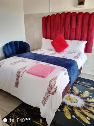 a bedroom with a large bed with a red headboard at Tenders Accommodation Rooms Mafikeng in Mahikeng