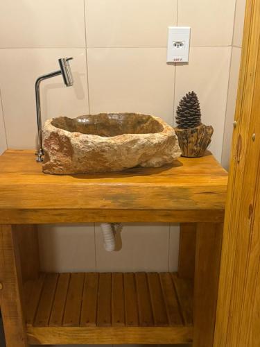 a stone sink sitting on a wooden table at Cabana refúgio do tico tico 07 in Cunha