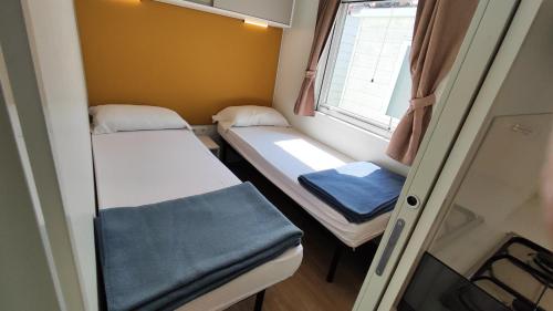 a small room with two beds and a window at Campeggio del Garda in Peschiera del Garda