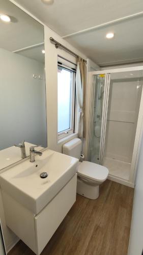 a white bathroom with a sink and a toilet at Campeggio del Garda in Peschiera del Garda