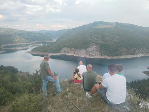 a group of people sitting on a hill overlooking a lake at Apartman Teodora Uvac in Nova Varoš