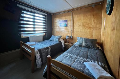 une petite chambre avec deux lits et une fenêtre dans l'établissement Hotel Low Cost "Colón", à Punta Arenas