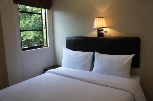 a bedroom with a white bed with a lamp and a window at Hotel Hong in Malacca