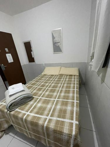 a bed in a room with a plaid blanket on it at Jardim Tropical in Bayeux