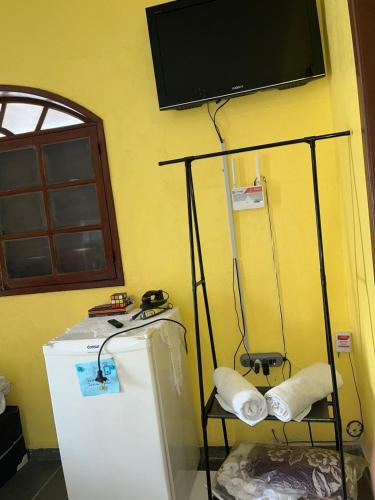 a room with a refrigerator and a tv on the wall at Viver a paz, praia & home office rua Nelson Pecegueiro do Amaral, 267, costa azul in Rio das Ostras