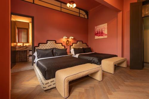 two beds in a room with red walls at Maison Lezard in Mexico City