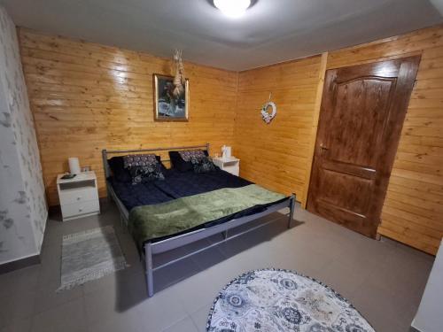 a bedroom with a bed and a wooden wall at Téli Berek Vendégház in Abod