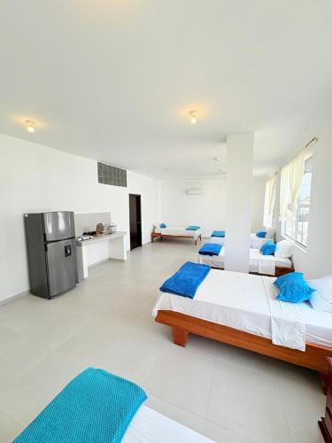 two beds in a white room with blue pillows at Marina Suite in Puerto Ayora