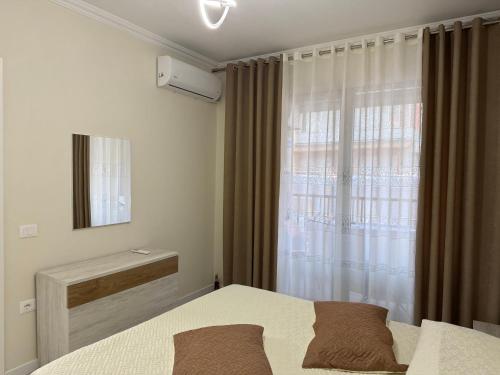 a bedroom with a bed and a window with a mirror at Valentinas Apartment in Korçë