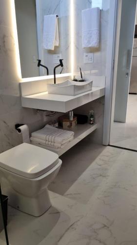 a white bathroom with a toilet and a sink at Casa Premium Adamantina in Adamantina
