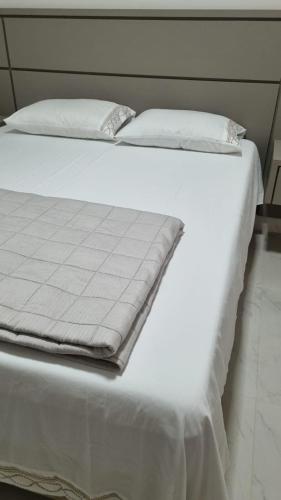 a white bed with white sheets and pillows on it at Casa Premium Adamantina in Adamantina