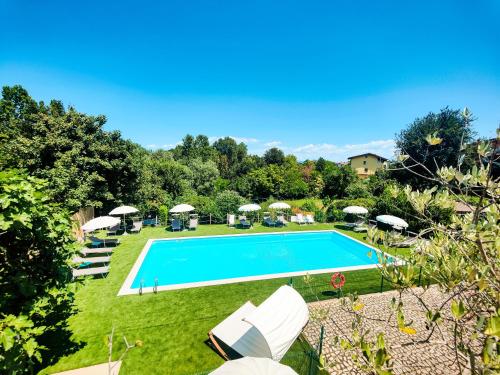 an image of a swimming pool in a yard with umbrellas at Albergo B&B Tenesi in Manerba del Garda