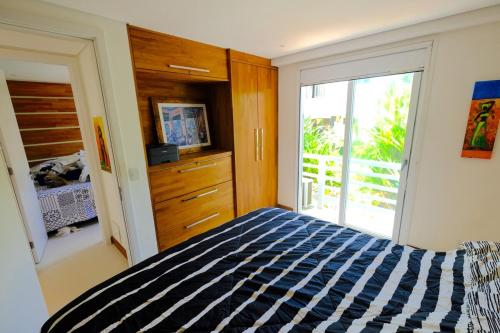 マタ・デ・サン・ジョアンにあるBeach Front Luxury, Praia do Forte, Feet in the Sand!のベッドとガラスの引き戸のある寝室