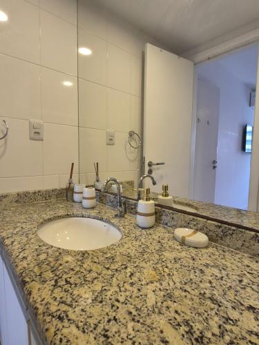 a bathroom counter with a sink and a mirror at Anfitrião Guiah! - Beira-mar e ao lado do Centro de Convenções in Salvador