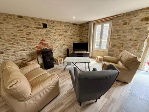 a living room with two couches and a stone wall at Ty Kermaudez in Paimpol