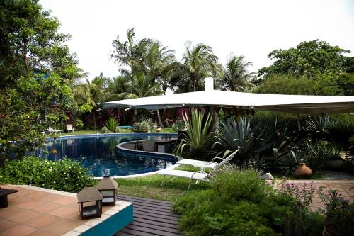 una piscina con sombrilla y sillas junto a un patio en Hospedaria Entre Amigos, en Búzios