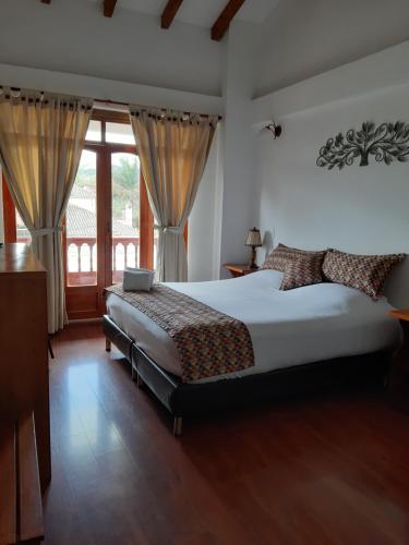a bedroom with a bed and a large window at Hotel El Giro in Villa de Leyva