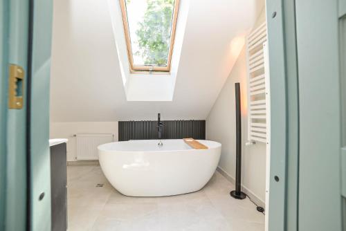 a white bath tub in a bathroom with a skylight at Homly Nook in Rīga