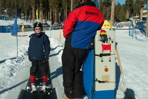 a man standing next to a boy with a snowboard at Austria Hof Lodge in Mammoth Lakes