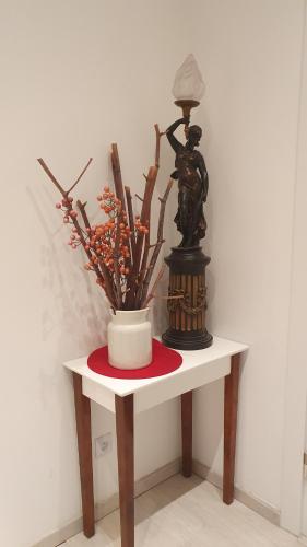 a table with a vase and a statue on it at Apartament City Center JAPAN - no smoking, free bottled water, coffea and tea in Koszalin