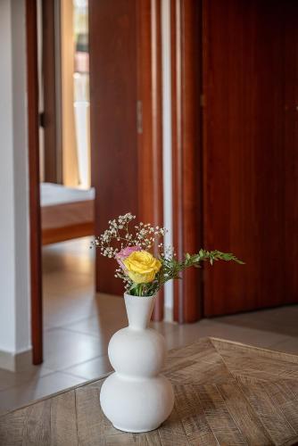 a white vase with flowers in it on a table at Light House Chania - 5 Min to Beach and Free Parking in Chania Town