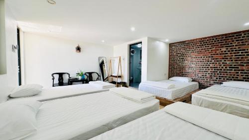 a bedroom with three beds and a brick wall at Queen House in Hoàng Ngà