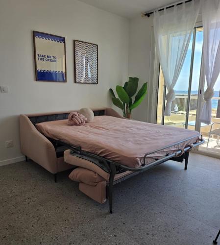 un lit dans une chambre avec une grande fenêtre dans l'établissement Deux pièces cosy, front de mer, terrasse et 2 SdB, à Antibes