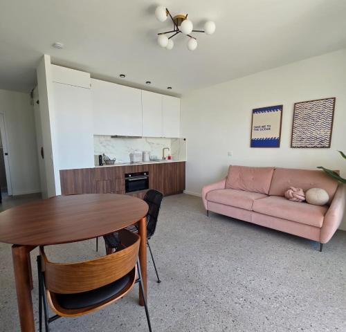 un salon avec un canapé rose et une table dans l'établissement Deux pièces cosy, front de mer, terrasse et 2 SdB, à Antibes