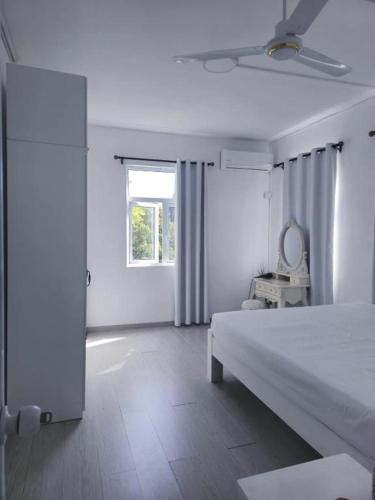 a white bedroom with a bed and a window at Family Perfect - Lovely New 2-Bedroom Apartment in Vacoas