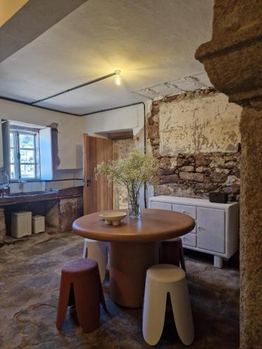 a kitchen with a table and stools in a room at Finca As Roeles Caión in Cayón