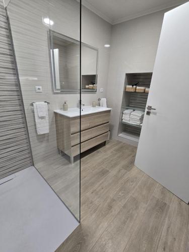 a bathroom with a sink and a glass shower at Brisa do Mar Azorean House in Maia