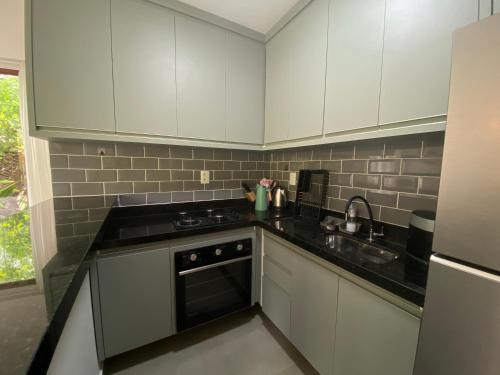 a kitchen with white cabinets and a black counter top at Casa Brisa - sossego a 50 mts da Praia da Bombaça em Barra Grande in Marau