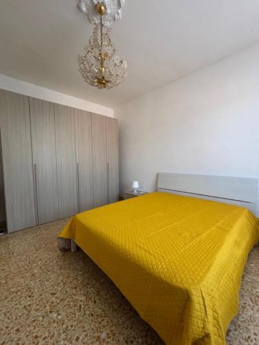 a bedroom with a yellow bed and a chandelier at Sunflower House in San Giuliano Terme