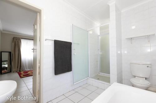 a white bathroom with a toilet and a sink at Midrand Premium Villa at Noordwyk in Midrand