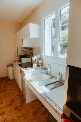 a white kitchen with a sink and a window at VillaNonna, jacuzzi, billards, pétanque, ping-pong, 12 couchages, terrasse plein soleil - Larès in Saint Remy sur Orne