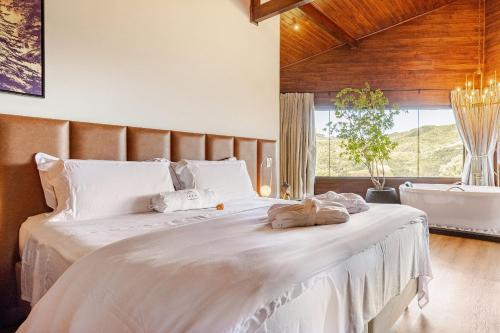 a bedroom with a large white bed with a large window at Vivenda Le Vin em Alfredo Wagner in Barracão