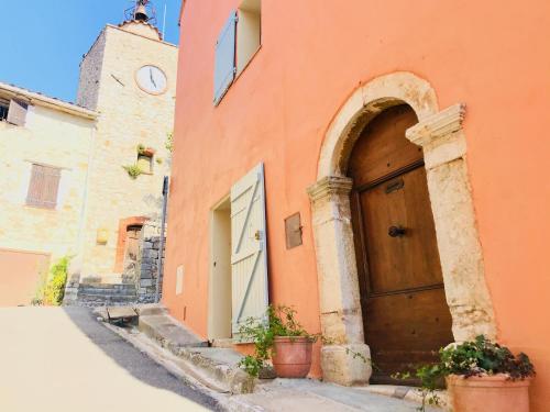 an orange building with a wooden door and a clock tower at Cabris Village - Elegant Family House in Cabris