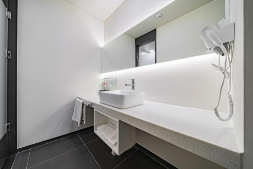 a white bathroom with a sink and a mirror at Pyeongtaek Stay Tourist Hotel in Pyeongtaek