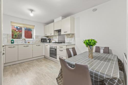 a kitchen with white cabinets and a table with chairs at Modern 4 Bedroom Detached House 66CL in Manchester