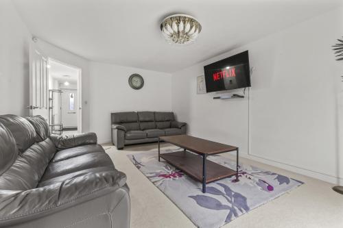 a living room with a leather couch and a table at Modern 4 Bedroom Detached House 66CL in Manchester