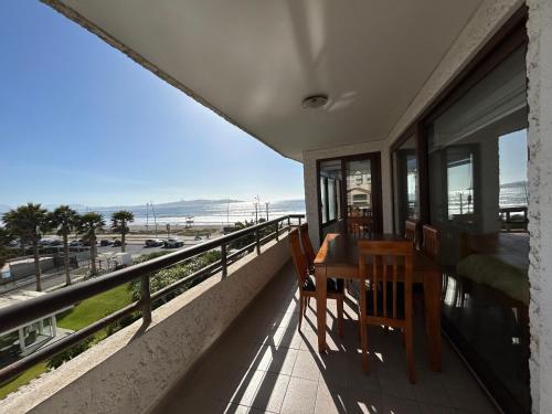 a balcony with a table and chairs and a view of the beach at Departamento frente al mar La Serena in El Cerrillo