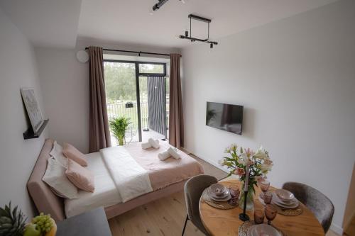 a bedroom with a bed and a table with a dining room at La Tereza Apartments in Ķesterciems