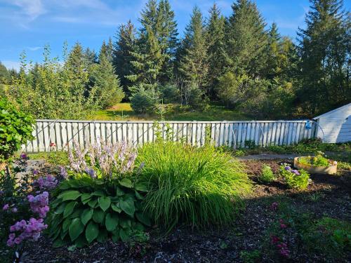 a garden with a white fence and some flowers at Garsoniera in Leirvåg