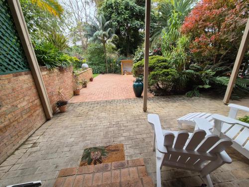 a patio with white chairs and a brick walkway at Emerald Escape in Emerald Beach