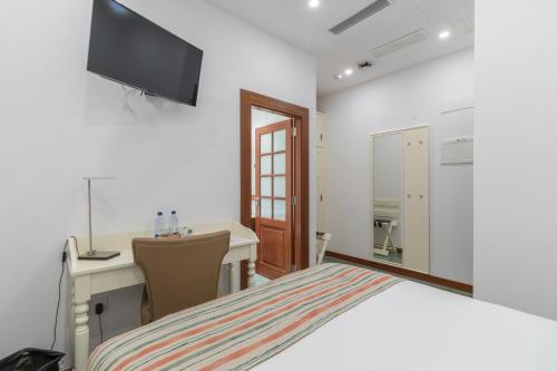 a bedroom with a bed and a desk and a television at Hotel Emblemático Holiday Time in Santa Cruz de la Palma