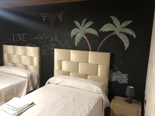 een slaapkamer met twee bedden en een zwarte muur met palmbomen bij Coparelia in Villarrobledo